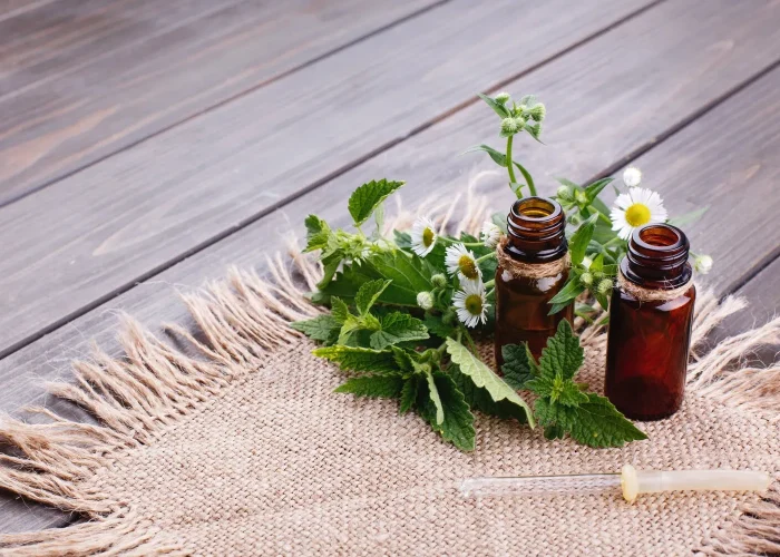 brown-bottles-with-oils-greenery-flowers-lie-brown-napkin